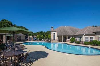 Resort style swimming pool with lounge chairs and umbrellas